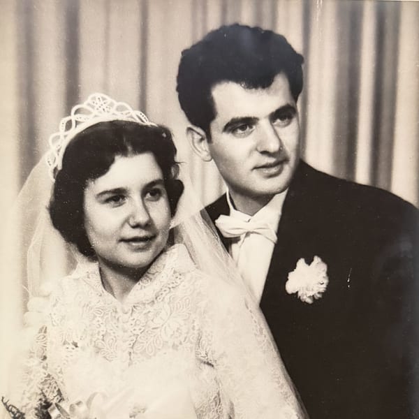 Black and white portrait of a smiling bride in a lace dress and groom in a tuxedo.