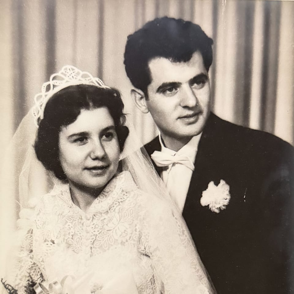 Black and white portrait of a smiling bride in a lace dress and groom in a tuxedo.